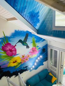 a room with a mural of flowers and a bird at Duplex Le Colibri 2-4p confort internet piscine plage à 5min in Sainte-Anne +11 photos