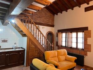 a living room with an orange chair and a staircase at Apartamentos Villa Julieta in Ruente