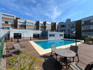 a swimming pool with chairs and a table next to a building at Residence Farol - Loft 210 - Vista mar Cardoso in Laguna