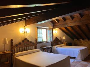 two beds in a room with wooden ceilings at Apartamentos Villa Julieta in Ruente
