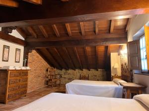 a bedroom with two beds and a stone wall at Apartamentos Villa Julieta in Ruente