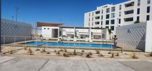 a woman standing next to a swimming pool next to a building at Steps to the beach, comfortable in Caldera
