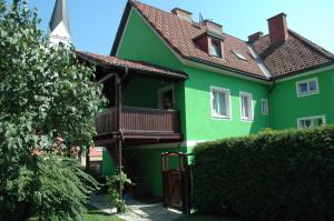 uma casa verde com uma varanda e uma cerca em City Apartment Vasiri em Knittelfeld