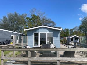 ラウエルウオーフにあるHaus mit dem schönsten Blick direkt am Meer BEST VIEWの木製デッキに座る青い小さな家