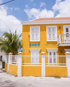 a yellow house with a palm tree in front of it at Bario Hotel in Willemstad
