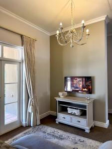 een woonkamer met een televisie en een kroonluchter bij Franschoek Lermitage Villa Two Bedroom Lake View in Franschhoek