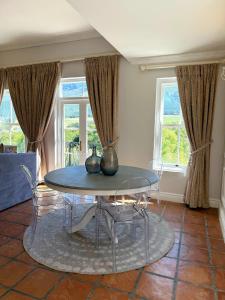 een eetkamer met een glazen tafel en stoelen bij Franschoek Lermitage Villa Two Bedroom Lake View in Franschhoek