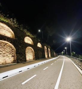 an empty road at night with lights on a bridge at Foce24 - City Garden - in Imperia +1 photo