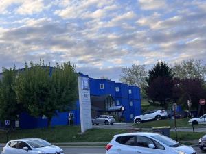 dos autos estacionados frente a un edificio azul en ibis budget Belfort Centre, en Belfort