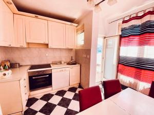 a kitchen with white cabinets and a checkered floor at Apartments Dani Free Parking in Sarajevo +17 photos