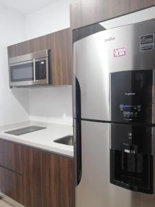 a kitchen with a stainless steel refrigerator and a microwave at Menesse mitdtown2 , AVE 25TH in Playa del Carmen