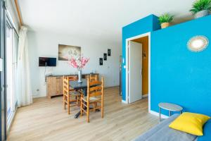 un salon avec une table et un mur bleu dans l'établissement Mer et Dune, à La Grande Motte