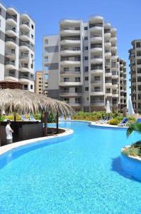 une grande piscine bleue avec des bâtiments en arrière-plan dans l'établissement قرية Batter sea أمام مارينا الساحل الشمالي, à El Qasaba esh Sharqīya