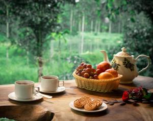 een tafel met twee kopjes koffie en een fruitmand bij De Spicewoods, AC Cabin, Pool, Couple only in Kalpatta