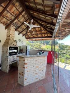 an outdoor kitchen with a fireplace and a ceiling fan at Casa em Secretário a 800 metros do centro de Secretário chacaradosolsecretario in Petrópolis