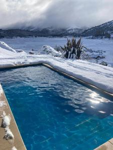 ein Schwimmbad im Schnee mit einem Gewässer in der Unterkunft Casa Patagonia in San Martín de los Andes