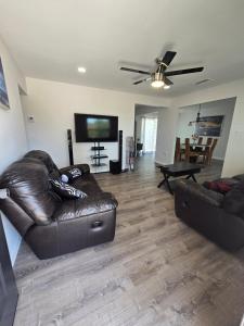 sala de estar con sofá de cuero y TV de pantalla plana en 3 bedrooms 2 bathrooms Charming Gulfport home near the beach, en San Petersburgo