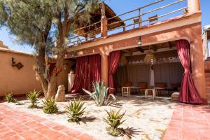 a patio with red curtains and a table and chairs at Kasbah ben Ali in El Kelaa des Mgouna