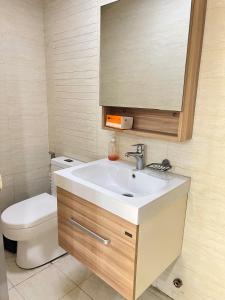 a bathroom with a sink and a toilet and a mirror at R&R Entire Rental Unit in Manila