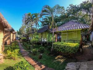 a green house in a village with palm trees at kohchang7seaview Bungalows in Ban Bang Bao