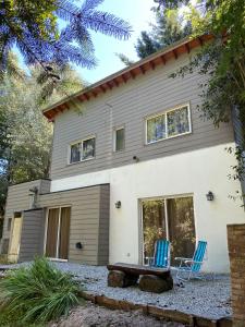 a house with two blue chairs in front of it at La Amapola in Villa La Angostura