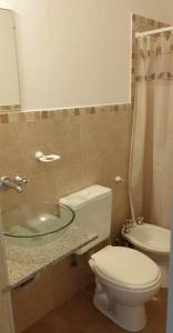 a bathroom with a toilet and a glass sink at Departamento del golf in Alta Gracia