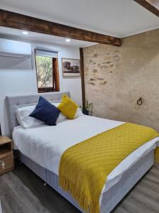 a bedroom with a large bed with yellow and blue pillows at The Bullock & Bridle Retreat at 58 in Mintaro