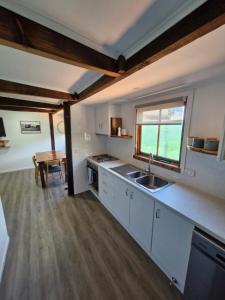 a kitchen with white cabinets and a sink and a table at The Bullock & Bridle Retreat at 58 in Mintaro