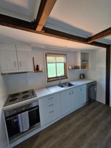 a kitchen with white cabinets and a sink and a window at The Bullock & Bridle Retreat at 58 in Mintaro
