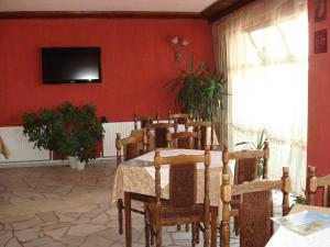 uma sala de jantar com uma mesa e uma televisão numa parede vermelha em Olympia em Kharmanli