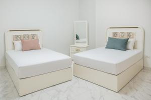 two beds in a white room with a mirror at Luxurious Chalet in Port Said Governorate with Breathtaking View in Port Said