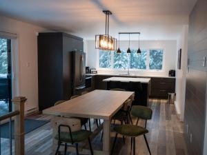 a kitchen with a wooden table and chairs at Cottage Quebec - Olivine in Petite-Rivière-Saint-François