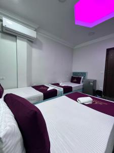 una stanza con tre letti e una luce rosa di Abdeen Cairo Hostel a Il Cairo