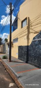 a yellow building with a stone wall next to a street at Casa requinte estilo Ap próx Fema Unesp in Assis