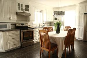a kitchen with white cabinets and a table with chairs at Vieux Beloeil appartement free Parking in Beloeil Village