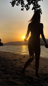 a woman standing on the beach at sunset at FOREST Nest with Self-Service Breakfast - Birds, Monkeys, Pet Friendly with a Fee in Subic Bay Intl