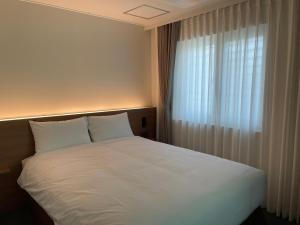 a bedroom with a large white bed with a window at MAPLE MANSION Hongdae in Seoul