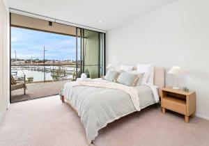 a white bedroom with a bed and a large window at Marinafront Retreat Shell Cove in Shellharbour