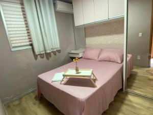 a bedroom with a pink bed with a table on it at Doce lar da Be in Ribeirão Preto