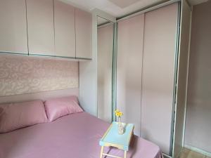 a small bedroom with a pink bed and a table at Doce lar da Be in Ribeirão Preto