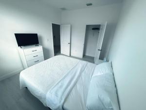 una camera da letto bianca con un letto e una televisione di Casa compartida vacacional a La Belle