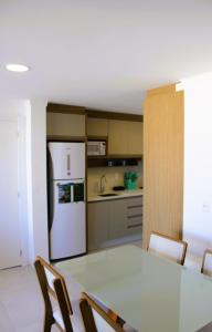 a kitchen with a table and a white refrigerator at Apto de duas suítes com vista mar - 100 metros da praia em Canasvieiras in Florianópolis