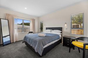 マウント・マウンガヌイにあるHome Sweet Home - Mt Maunganui Holiday Homeのベッドと机とテーブルのある寝室