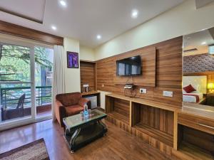 a living room with wood paneled walls and a tv at The Cedar Vatika Hotel and Restaurant in Dharamshala