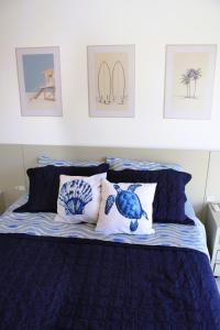 a bed with blue and white pillows and pictures on the wall at Apto de duas suítes com vista mar - 100 metros da praia em Canasvieiras in Florianópolis
