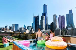 a man and a woman sitting on the edge of a swimming pool at Space Hotel in Melbourne