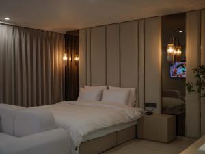 a bedroom with a large bed with white sheets at Vibe Hotel Gimhae Jangyu in Gimhae