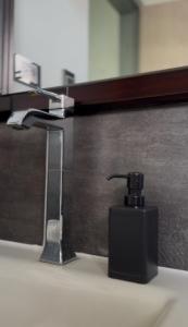 a black soap dispenser on a sink in front of a mirror at Casa Vittoria in Cali