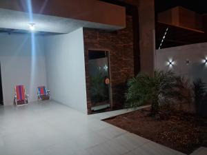Habitación blanca con 2 sillas y una planta en Quarto da Tay, en Paranavaí
