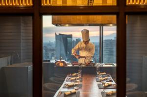 a chef in a kitchen with a table of food at ANA InterContinental Tokyo by IHG in Tokyo